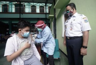 Didampingi Gubernur DKI Jakarta, Anies Baswedan, seorang pelajar tampak menerima suntikan vaksin covid-19 di salah satu sekolah di Jakarta.